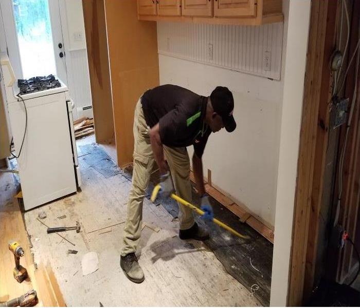 SERVPRO® technician removing wet hardwood floor