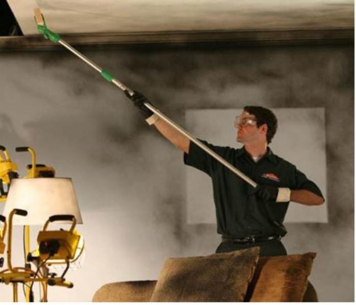Technician cleaning soot from fire damage on ceiling